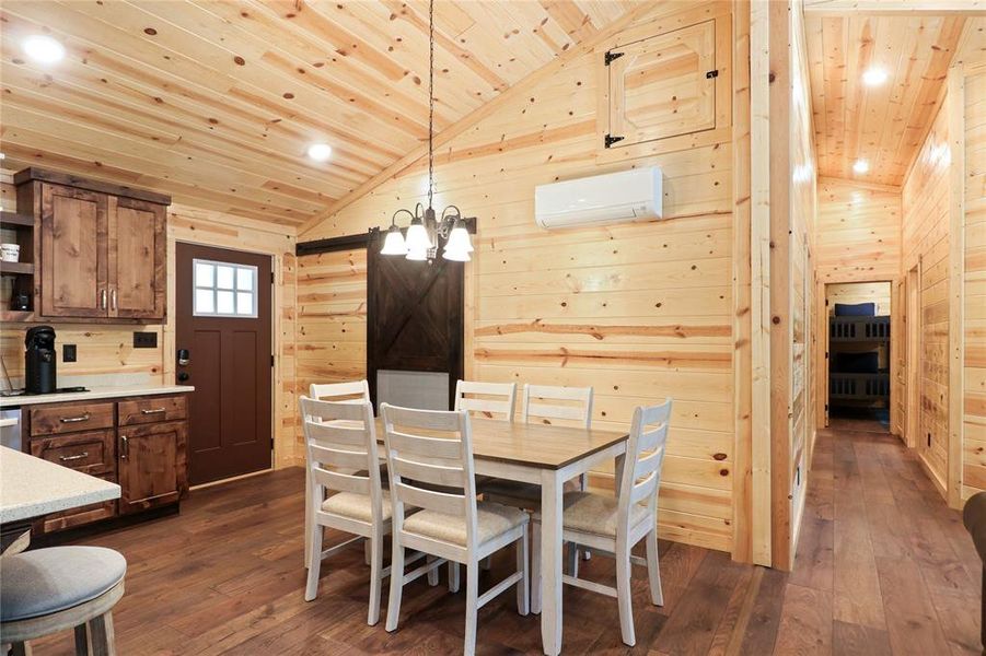 Dining area featuring dark wood-type flooring, wooden walls, wood ceiling, and a wall mounted air conditioner
