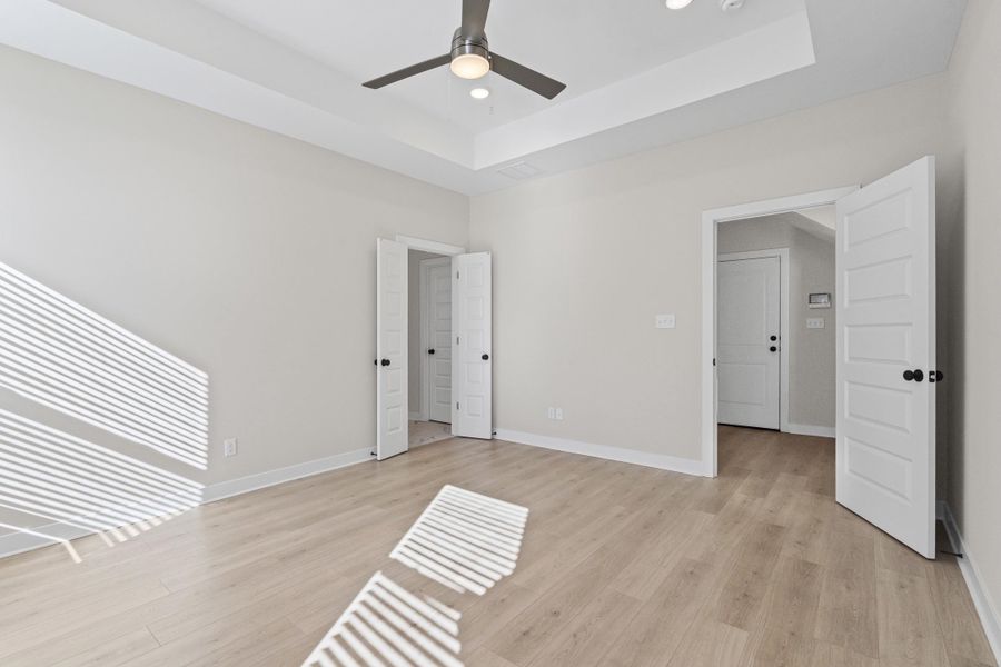 Unfurnished room with light wood-type flooring, a tray ceiling, and recessed lighting Unfurnished room with light wood-type flooring, a tray ceiling, and recessed lighting