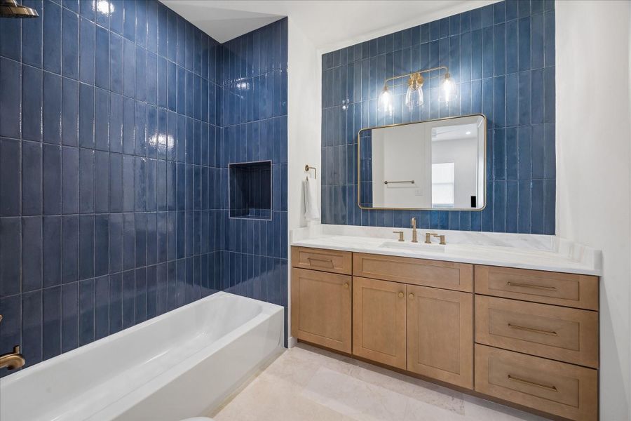 First floor bathroom with natural stone tile floors and marble countertops.