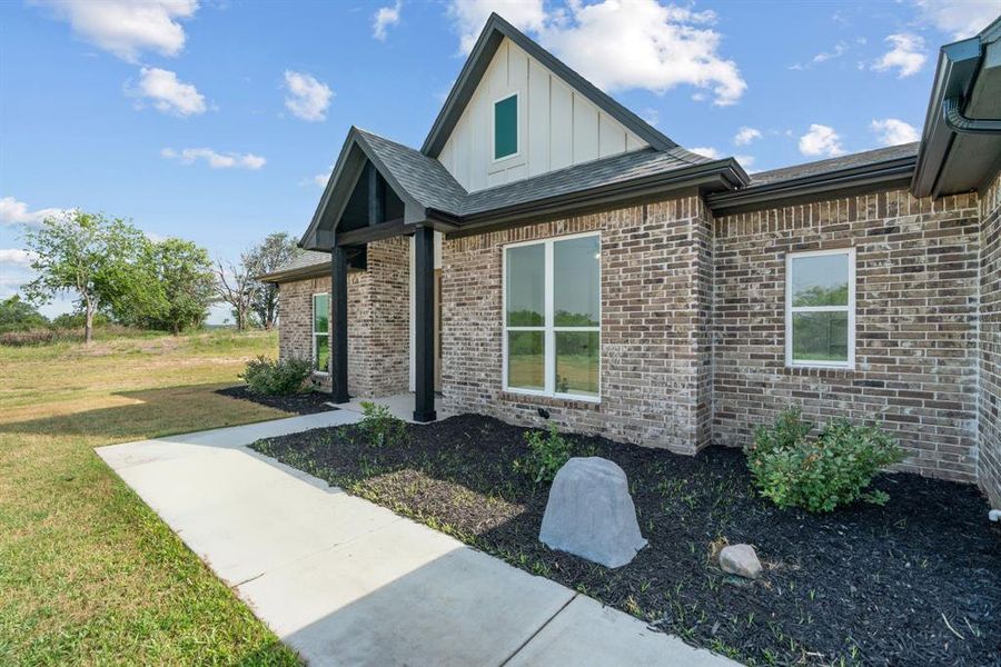 Craftsman house with board and batten siding, a front yard, roof with shingles, and brick siding