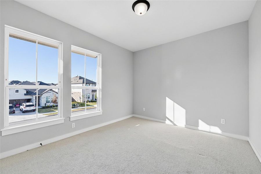 Plentiful natural light streams through tall windows over soft carpeted floors.