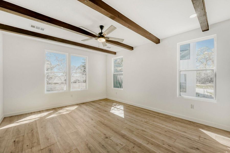 Spare room with a ceiling fan, light wood-style floors, beam ceiling, and plenty of natural light