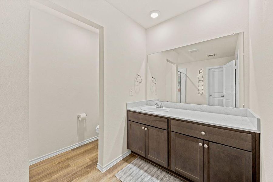 Bathroom vanity featuring a single sink, light-toned countertop, and dark wood-finish cabinetry Bathroom vanity featuring a single sink, light-toned countertop, and dark wood-finish cabinetry