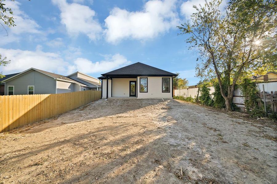 Rear view of property featuring a patio, a fenced backyard, driveway, and a shingled roof
