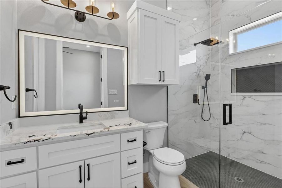 Modern bathroom featuring a glass-enclosed shower with contrasting dark tile flooring and a built-in niche