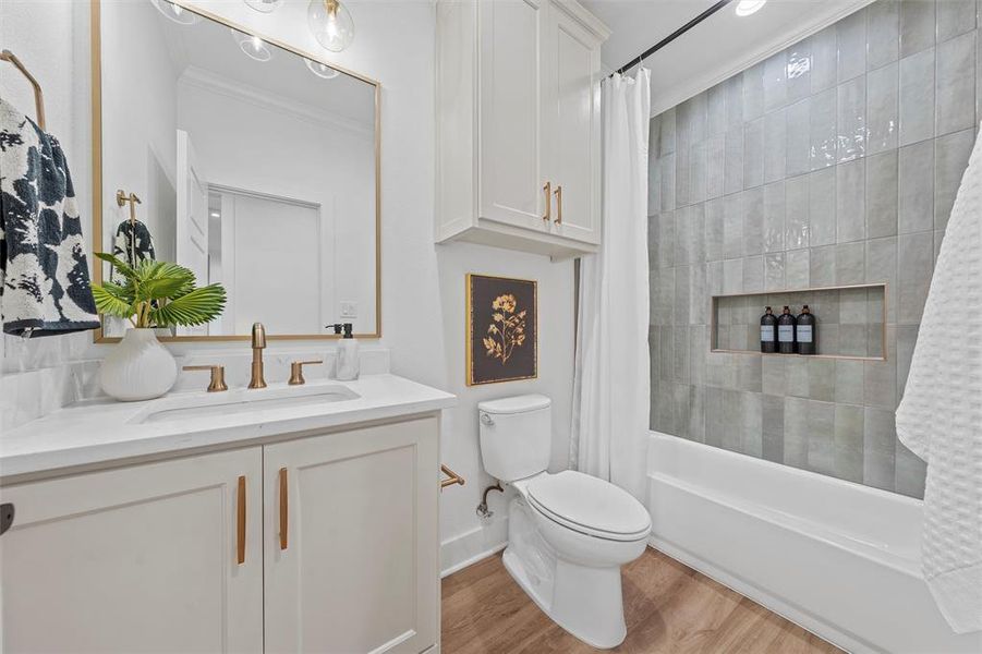 Full bath featuring vanity, shower / bath combo with shower curtain, wood finished floors, and ornamental molding