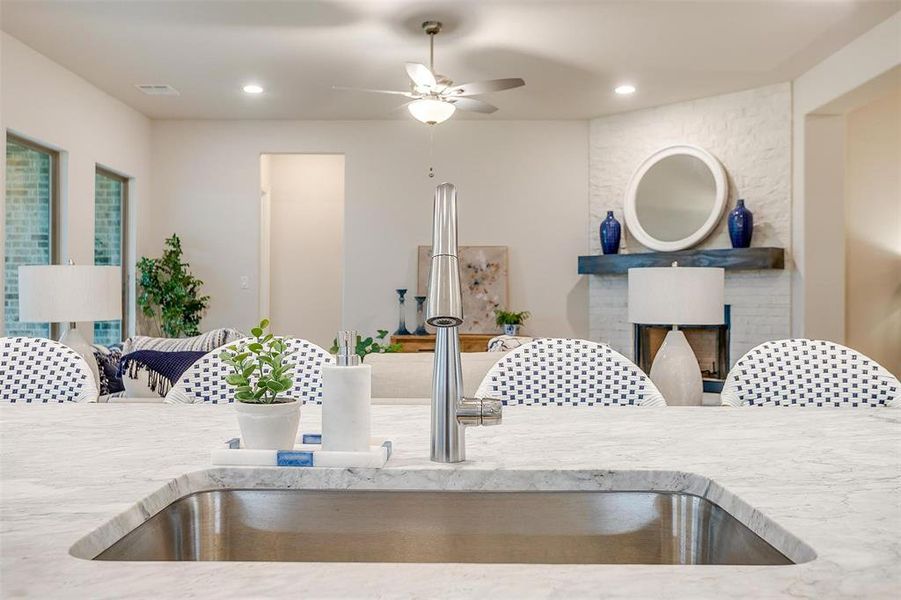 Kitchen with light stone countertops, ceiling fan, a fireplace, and sink