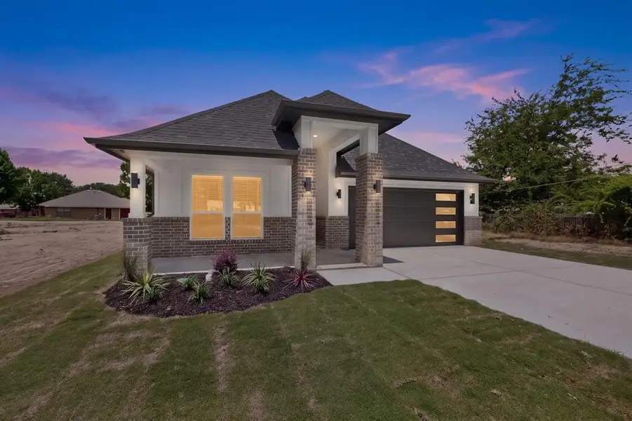 Contemporary exterior featuring brick and white siding, a dark asphalt shingle roof, and a modern garage door with frosted panels