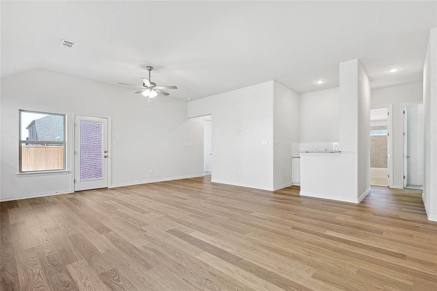 Unfurnished room with light hardwood / wood-style floors, lofted ceiling, and ceiling fan