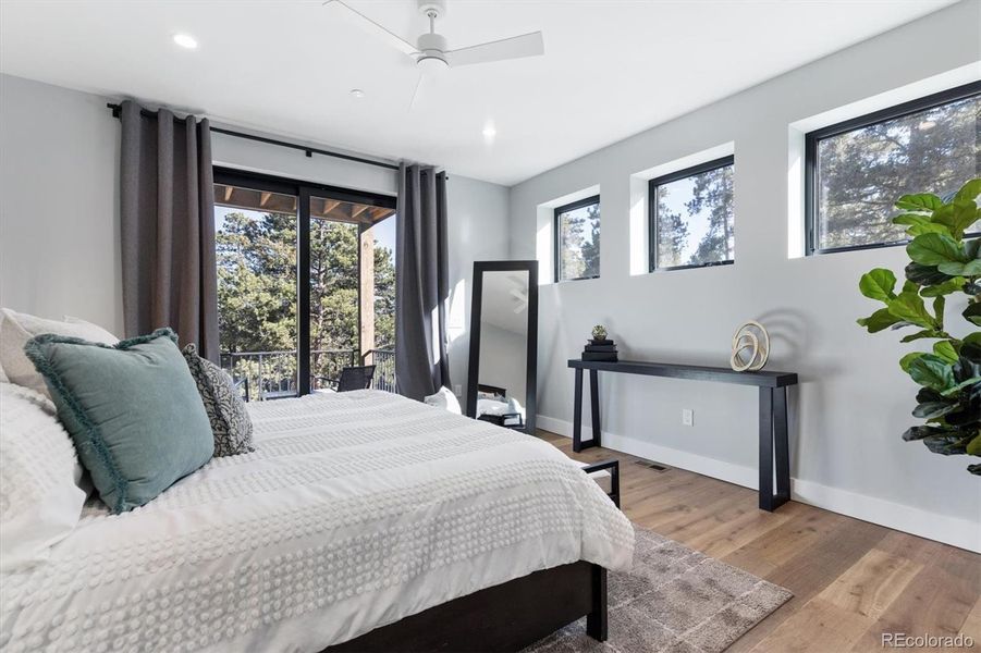 Primary bedroom suite with hardwood floors, abundant natural light, sliding glass door and access to a private covered deck Primary bedroom suite with hardwood floors, abundant natural light, sliding glass door and access to a private covered deck