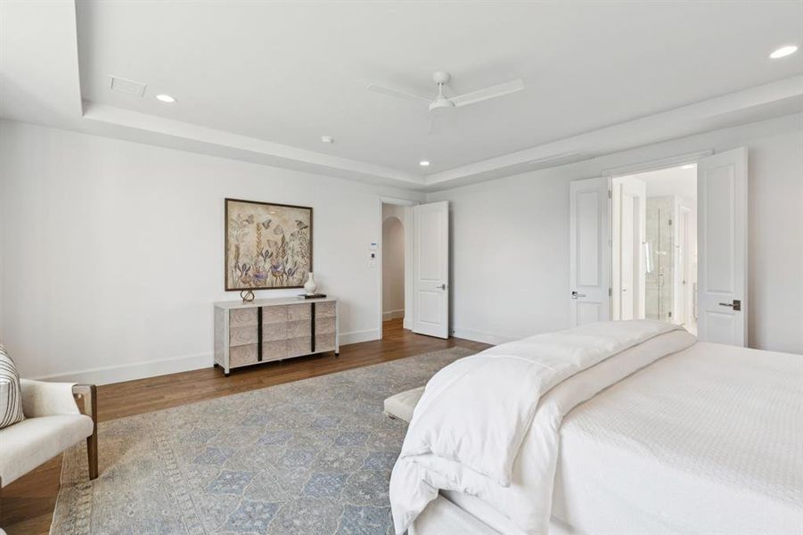Bedroom featuring arched walkways, recessed lighting, a raised ceiling, ceiling fan, and wood finished floors Bedroom featuring arched walkways, recessed lighting, a raised ceiling, ceiling fan, and wood finished floors
