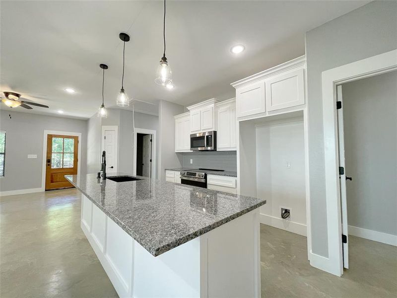 Kitchen featuring dark stone counters, white cabinetry, stainless steel appliances, sink, and ceiling fan