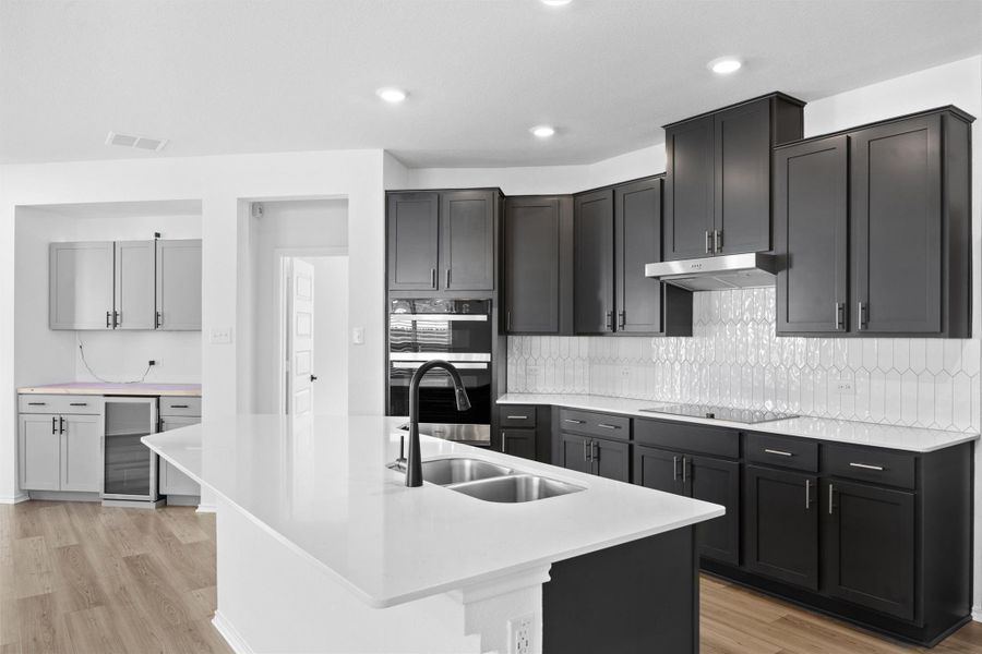 Kitchen featuring light wood-type flooring, backsplash, light stone counters, beverage cooler, and recessed lighting