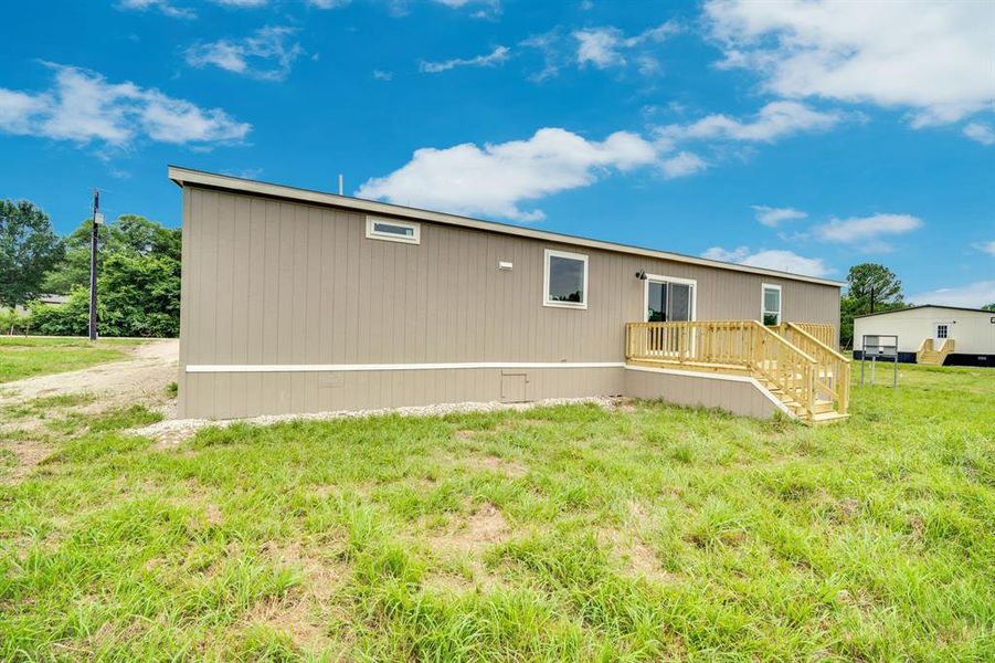 Light brown vertical siding exterior with a wood deck and staircase
