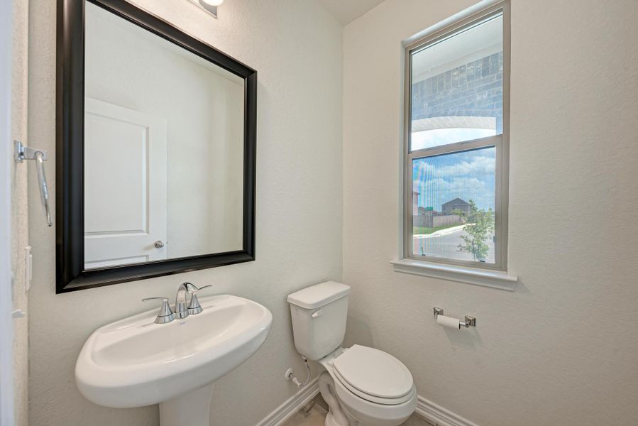 A well-lit powder room offers clean lines and a contemporary pedestal sink.