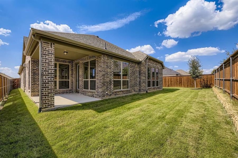 Back of house with a fenced backyard, brick siding, and a patio area