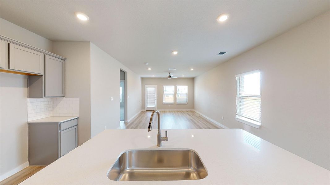 Kitchen with gray cabinetry, open floor plan, light wood-style floors, recessed lighting, and tasteful backsplash