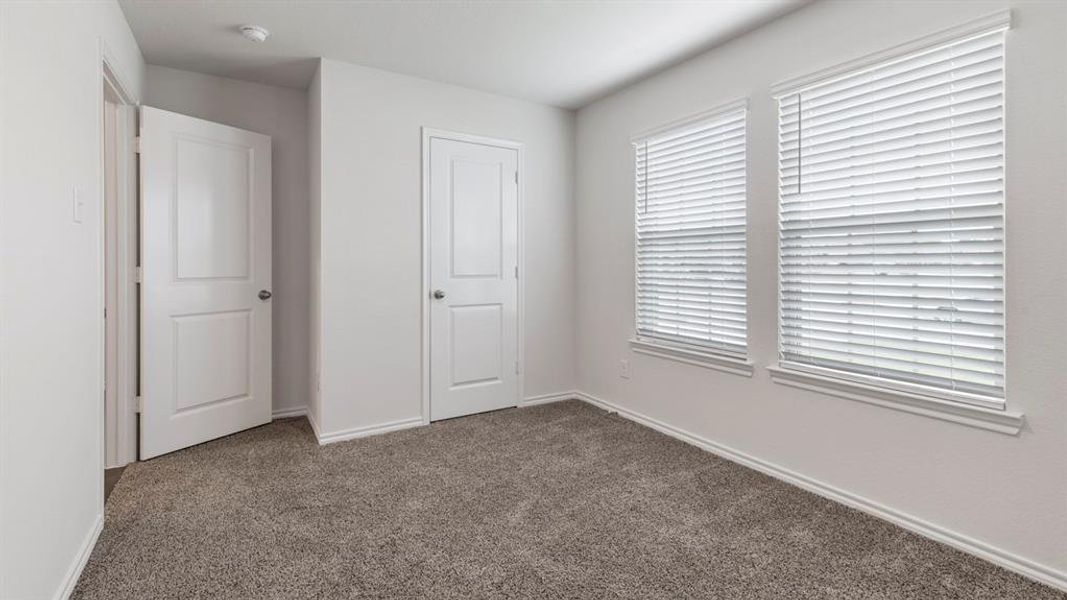 Unfurnished bedroom featuring dark colored carpet and baseboards