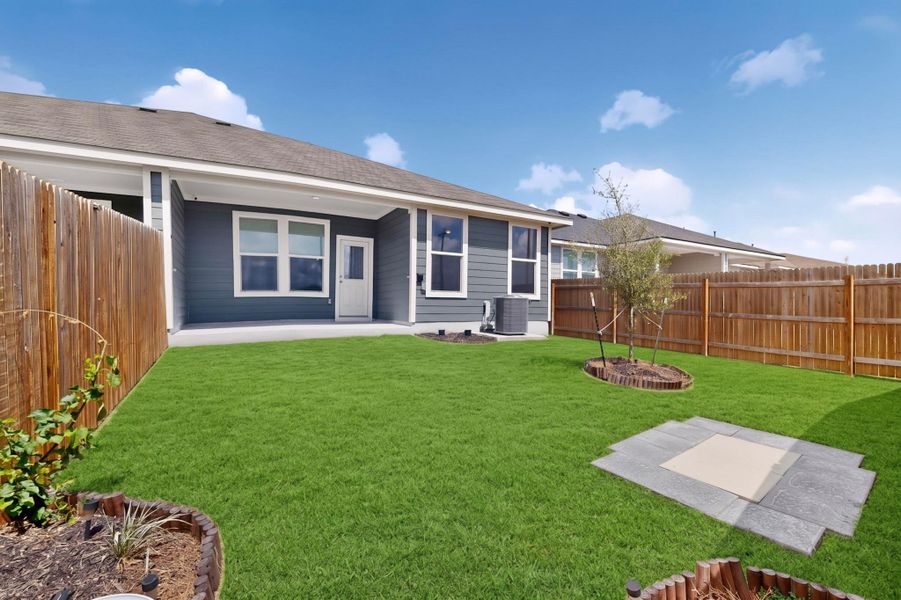A spacious green lawn sits enclosed by privacy fencing behind a modern residential structure. A spacious green lawn sits enclosed by privacy fencing behind a modern residential structure.