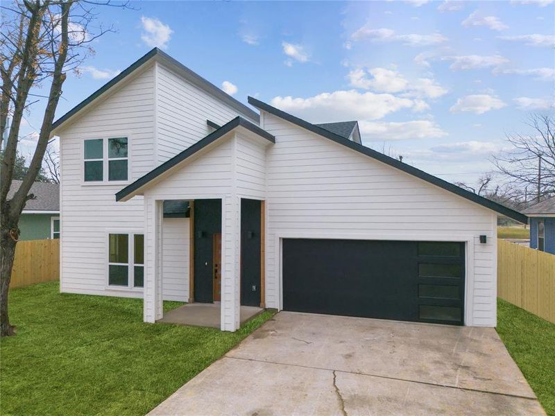 View of front of property with a very spacious front yard and a garage with electrical charger station.