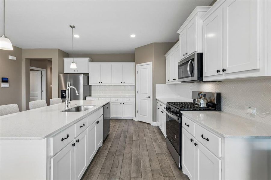 Contemporary kitchen featuring white shaker cabinetry, light-toned countertops, and wood-finish flooring