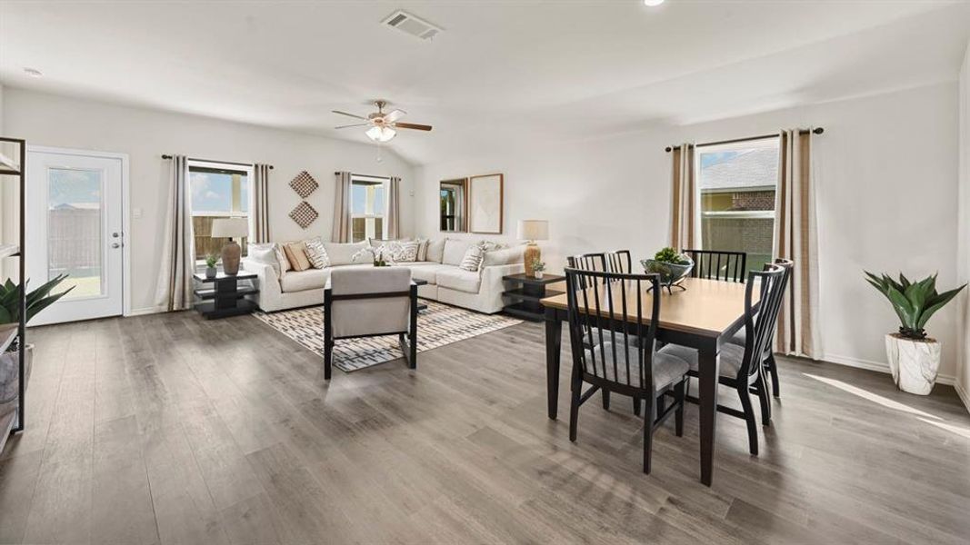 Open concept living area with light-colored flooring, a ceiling fan, and large windows providing natural light