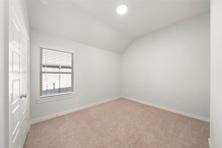 Carpeted empty room with vaulted ceiling