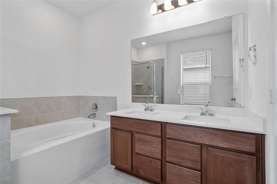 This primary bathroom is definitely move-in ready! Featuring a walk-in shower with tile surround, garden tub to soak after a long day, dark stained cabinets with light countertops, spacious walk-in closet with shelving, high ceilings, custom paint, sleek and dark modern finishes.