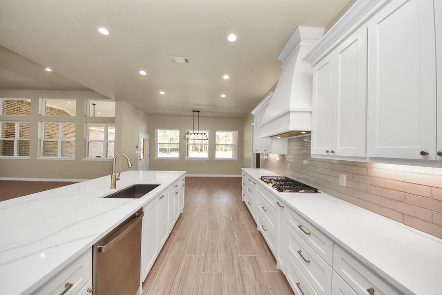 The large island with a sink, connects to a spacious living area with ample natural light from large windows.