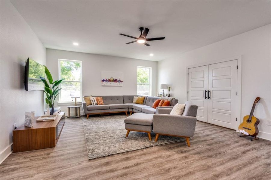 Living area with a ceiling fan, healthy amount of natural light, wood finished floors, and recessed lighting