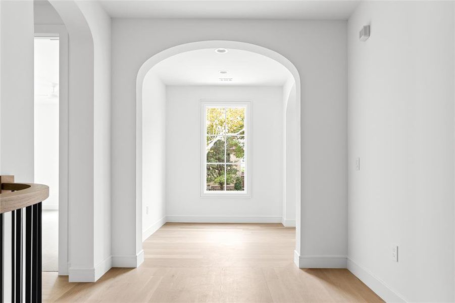 Corridor featuring arched walkways and light wood-type flooring