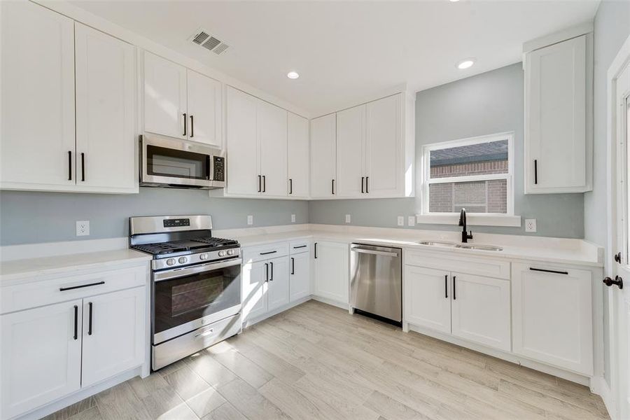 Kitchen featuring white cabinetry, sink, light hardwood / wood-style flooring, and appliances with stainless steel finishes