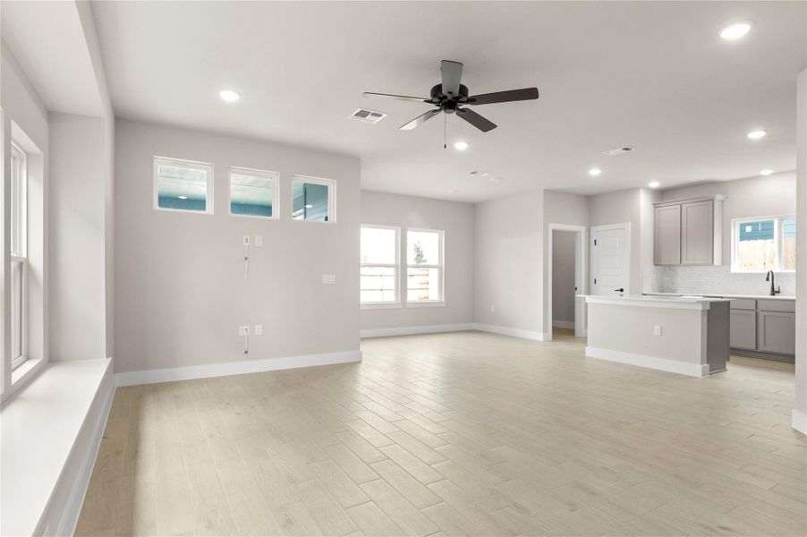 Unfurnished living room with ceiling fan, plenty of natural light, recessed lighting, baseboards, and light wood finished floors Unfurnished living room with ceiling fan, plenty of natural light, recessed lighting, baseboards, and light wood finished floors