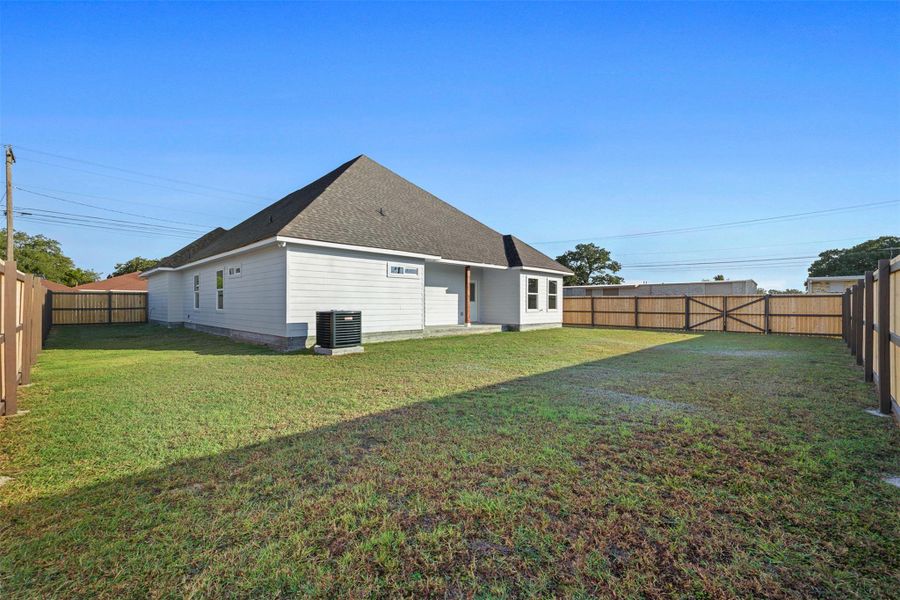 Back of house with a fenced backyard, a patio area, and roof with shingles Back of house with a fenced backyard, a patio area, and roof with shingles