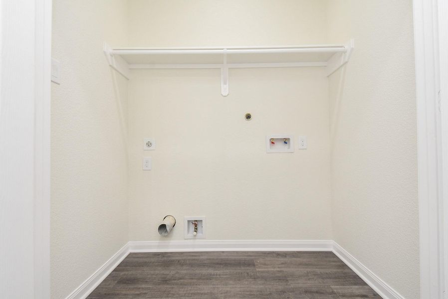 An empty closet with shelves and hooks, textured walls, wood-like flooring, and electrical outlets. An empty closet with shelves and hooks, textured walls, wood-like flooring, and electrical outlets.
