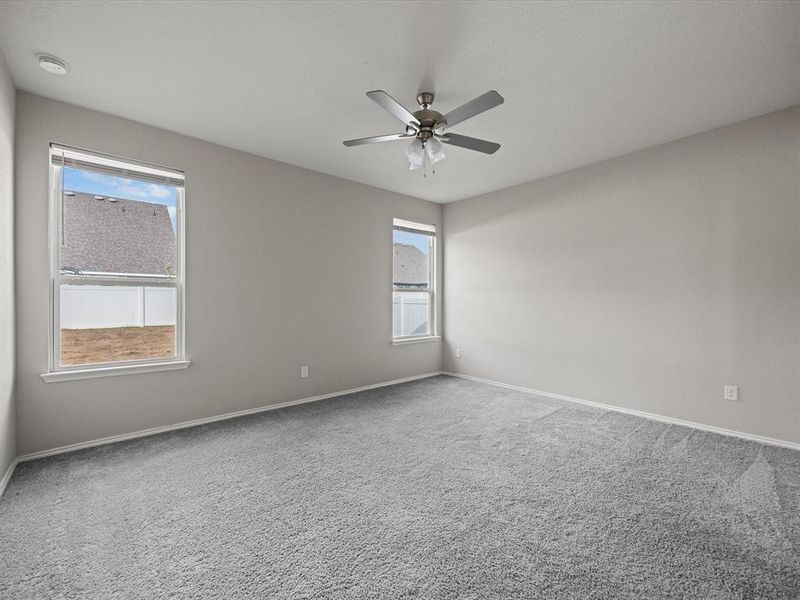 Empty room featuring plenty of natural light, carpet flooring, and a ceiling fan Empty room featuring plenty of natural light, carpet flooring, and a ceiling fan