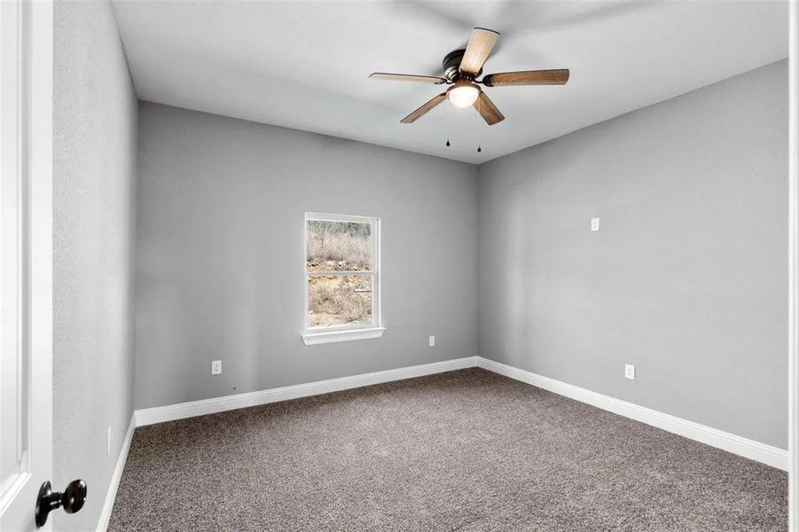 Carpeted empty room featuring ceiling fan and baseboards