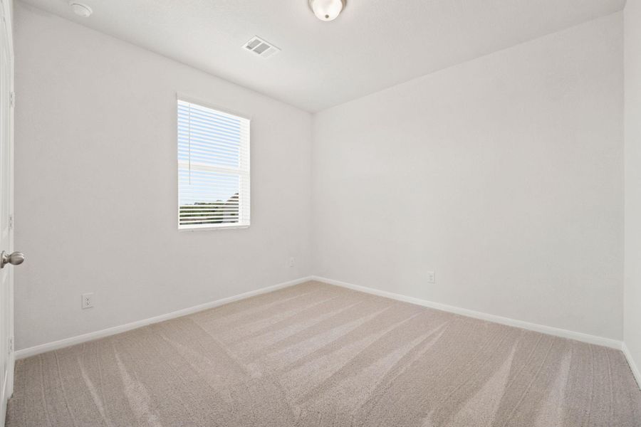 Plush carpeting and a classic window create a serene atmosphere in this bedroom.