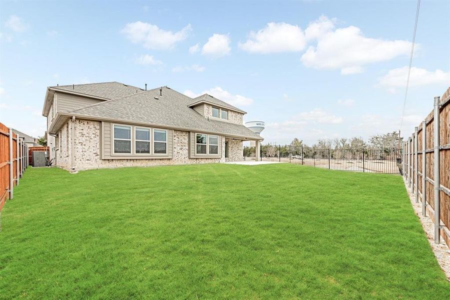 Rear view of property featuring a fenced backyard, a shingled roof, a patio area, and brick siding