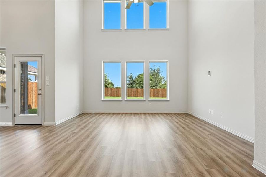 Unfurnished living room with a high ceiling, light wood-style flooring, and ceiling fan