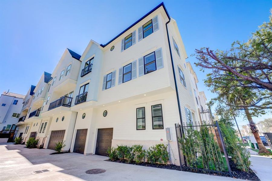 Fenced unit with an abundance of windows, shutters, recessed lighting, and double garage doors.