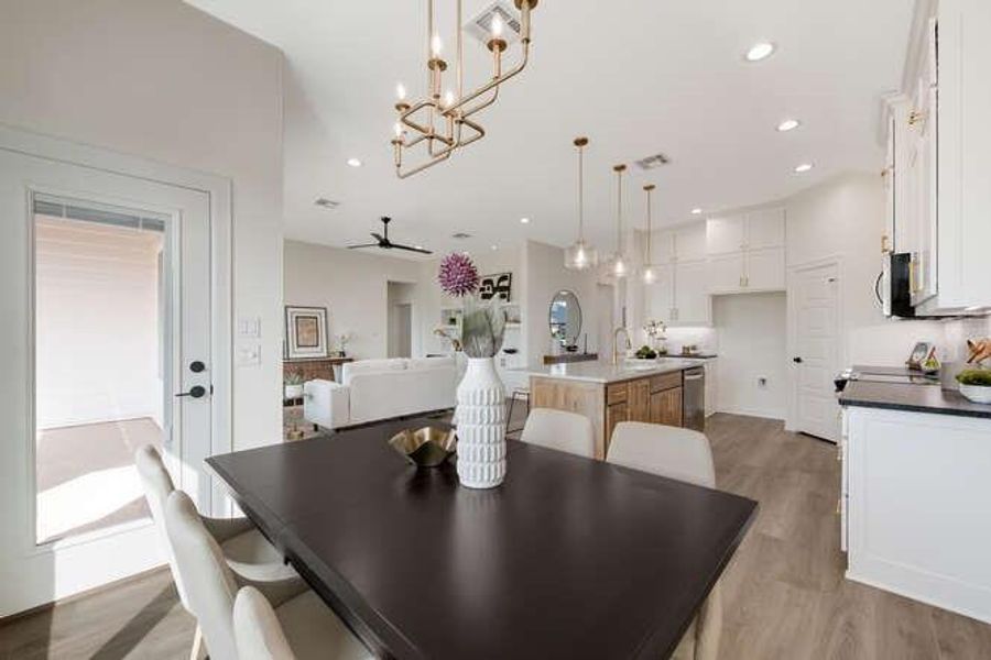 Dining space featuring light wood-style floors, ceiling fan, recessed lighting, and a chandelier Dining space featuring light wood-style floors, ceiling fan, recessed lighting, and a chandelier