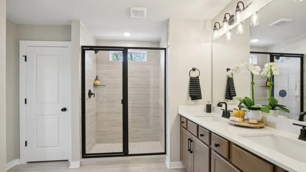 Bathroom with dual-vanity quartz countertop, glass shower enclosure, and linen closet