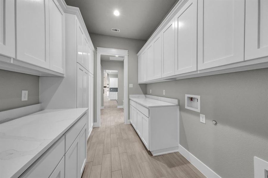 Laundry area with cabinets, light wood-type flooring, and washer hookup