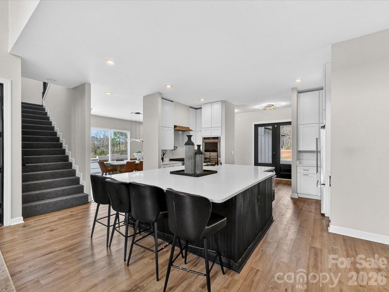 Modern open kitchen featuring a large island with seating, sleek cabinetry, and seamless flow to dining and outdoor spaces.
