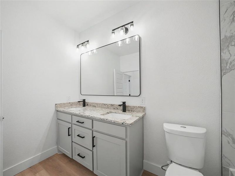 Bathroom featuring a double vanity with light gray cabinetry, speckled countertops, and matte black fixtures Bathroom featuring a double vanity with light gray cabinetry, speckled countertops, and matte black fixtures