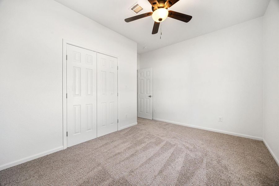 Charming second bedroom with plush carpet, generous closet space, and a sleek ceiling fan for added comfort. Charming second bedroom with plush carpet, generous closet space, and a sleek ceiling fan for added comfort.