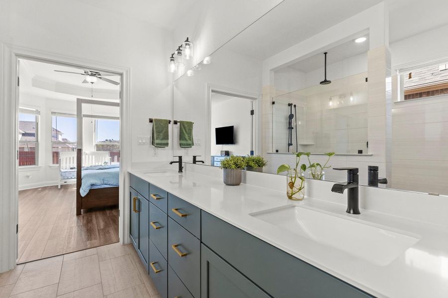 Full bathroom with plenty of natural light, double vanity, a stall shower, ensuite bath, and a raised ceiling