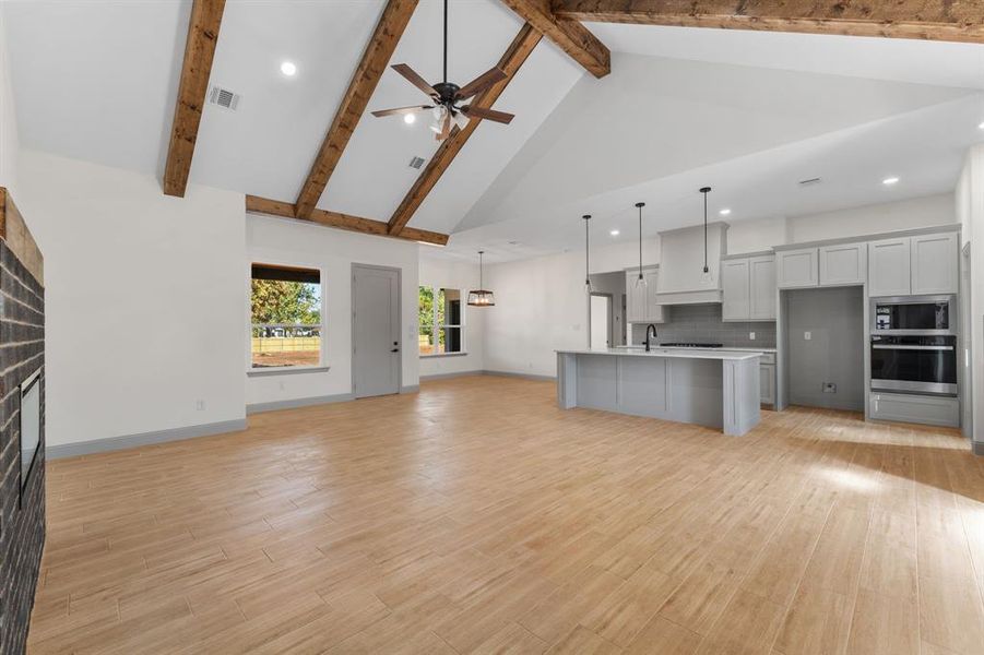 Kitchen with open floor plan, high vaulted ceiling, hanging light fixtures, recessed lighting, and stainless steel appliances