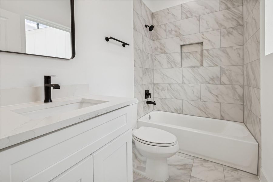 This bathroom features a sleek, modern design with a white marble-tiled shower and tub combo. It includes a stylish vanity with a marble countertop and black fixtures, creating a clean and elegant look. This bathroom features a sleek, modern design with a white marble-tiled shower and tub combo. It includes a stylish vanity with a marble countertop and black fixtures, creating a clean and elegant look.